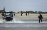 Des policiers poursuivent des migrants candidats à la traversée de la Manche pour les empêcher de monter à bord d'une embarcation le 26 avril 2024 à Loon-Plage, dans le Nord