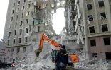 Un ouvrier observe une pelleteuse qui déblaie les décombres du bâtiment de l'administration régionale de Mykolaïv touché par des roquettes russes le 29 mars 2022
