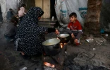 Une Palestinien prépare le repas de fin de jeûne au deuxime jour du ramadan dans un camp pour personnes déplacées à Rafah, dans le sud de la bande de Gaza, le 12 mars 2024