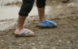 Dans les allées du camp, qui s'étend sur plus d'un kilomètre, hommes et femmes pataugent dans la boue. Certains ont recouvert leurs chaussures de sacs en plastique en guise de protection