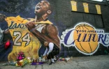 Un fan allume une bougie devant une fresque représentant Kobe Bryant, le 26 janvier 2020 à Los Angeles 