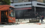 Des manifestants montent une barricade près d'un bus en flammes durant des émeutes à Santiago, le 19 octobre 2019