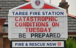 "Conditions catastrophiques mardi, préparez-vous", lit-on sur la caserne de pompiers de Taree Des carcasses calcinées de véhicules après des incendies de brousse à Old Bar à 350 kms au nord de Sydney le 11 novembre 2019