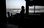 Une commerçante regarde l'océan depuis son petit commerce sur la plage d'El Zonte, au Salvador, le 23 juillet 2024