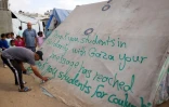 Un homme écrit un message de remerciement aux étudiants américains sur une tente dans un camp de déplacés palestiniens à Rafah, dans le sud de la bande de Gaza, le 27 avril 2024