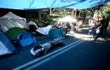 Des personnes récemment expulsées d'un centre social à Rome campent à l'extérieur du centre, le 11 août 2026