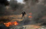Un manifestant palestinien tire un pneu en feu durant les heurs frontaliers avec l'armée israélienne, le 11 mai 2018 dans la bande de Gaza