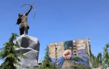 Une sculpture moderne d'Arash l'Archer, figure légendaire de la mythologie persane, devant affiche géante sur la façade d'un immeuble représentant le détroit d'Ormuz avec l'inscription en persan "À jamais dans la main de l'Iran", le 25 mai 2026 à Téhéran