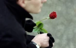 Un homme tient une rose devant l'église de Jarnac lors des funérailles de l'ancien président François Mitterrand, le 11 janvier 1996