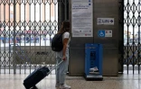 Une voyageuse lit des informations sur la circulation des transports en commun à la station de métro Victoria, le 19 août 2022 à Londres lors d'une grève pour les salaires