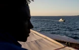 Un migrant regarde une vedette des autorités italiennes escorter le Sea Watch à son arrivée à Catane, le 31 janvier 2019