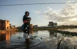 Des habitants marchent le 28 janvier 2022 dans le quartier inondé d'Ankasina à Antananarivo, capitale de Madagascar, après le passage de la tempête tropicale Ana
