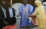 Muhammadu Buhari (c), accompagné de sa femme  Aisha dépose un bulletin dans un bureau de vote de sa ville natale Daura (nord-ouest) du Nigéria, le 23 février 2019