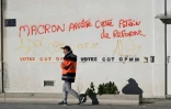 Un docker passe devant un slogan contre la réforme des retraites, lords du blocage du port autonome de Marseille, le 12 décembre 2019