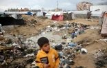 Un enfant joue au milieu des déchets, dans un camp de déplacés à  Nousseirat, dans le centre de la bande de Gaza, le 23 février 2025