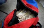 Une femme montre un sac rempli de billets de 100 bolivars qu'elle veut changer à la banque centrale à Caracas, le 16 décembre 2016