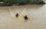 Des pêcheurs utilisent des filets pour attraper des poissons alors qu'ils sont allongés sur des calebasses dans la rivière Sokoto, appelée localement Maten Fada, à Argungu, dans l'État de Kebbi, au nord du Nigeria, le 12 avril 2025