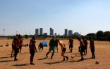 Des hommes s'entraînent au football sur une pelouse désséchée à Londres, le 13 août 2022