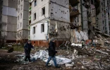 Un couple marche devant un immeuble résidentiel atteint par les bombardements sur la ville ukrainienne de Tcherniguiv le 4 mars 2022