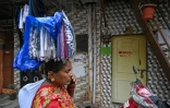 Une vendeuse ambulante passe devant des maisons destinées à être réaménagées dans le cadre d'un projet de rénovation urbaine du bidonville de Dharavi, le 8 juillet 2025 à Bombay, en Inde