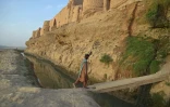 Un homme franchit un pont devant le palais Qal-e-Kohna près de Lashkar Gah, dans la province du Helmand, le 27 mars 2021 en Afghanistan