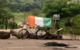 Le drapeau ivoirien et des troncs d'arbres pour bloquer une route d'accès à Daoukro, le 2 novembre 2020 