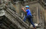 Un jardinier grimpe sur une corniche extérieure au temple d'Angkor Wat, le 12 octobre 2020