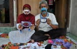 Dwi Rahayu (g) et son mari Elfiandi, tous deux sourds et muets, présentent leurs masques transparents à Yogyakarta, en Indonésie, le 22 avril 2020