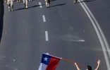 Un protestataire tenant un drapeau chilien s'avance vers des soldats durant des manifestations à Santiago, le 20 octobre 2019