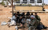 Des combattants tribaux se reposent près d'un barrage mis en place par les forces gouvernementales après leur déploiement à Busra al-Harir, dans la province de Deraa, dans le sud de la Syrie, le 21 juillet 2025