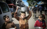 Des enfants transportent des ustensiles en se rendant à une distribution de nourriture à Khan Younès, au sud de la bande de Gaza, le 7 mars 2024