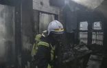 Un pompier éteint une maison en feu touchée par des roquettes russes dans le quartier Shevchenkivsky de Kiev, en Ukraine, le 23 mars 2022