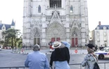 Des passants regardent la façade de la cathédrale Saint-Pierre-et-Saint-Paul de Nantes touchée par un incendie, le 19 juillet 2020