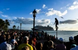 Une foule de touristes observe un artiste de rue, un bateau de croisière au large, le 11 avril 2022 à Key West, en Floride