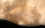 Des avions de lutte contre les incendies larguent de l'eau sur un feu de forêt près du village de Cebreros, dans la province d'Ávila, en Espagne, le 27 juillet 2026