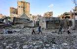 Des habitants passent devant un immeuble résidentiel touché la veille par une frappe israélienne dans le quartier d'Al-Ramal à Gaza, le 16 mai 2026