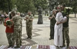 Des couples de militaires ukrainiens, Kristina et Vitali Orlich (à droite), ainsi que Kristina Liouta et Volodymyr Mikhalchouk (à gauche), s'embrassent après avoir été mariés dans la ville de Droujkivka, dans l'est de l'Ukraine, le 12 juin 2022
