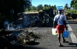 Un homme portant des bouteilles d'eau traverse le barrage de La Boucan (Guadeloupe), le 29 novembre 2021