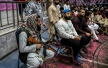 Un agent de sécurité taliban (g) assiste au concours de culturisme Mr Afghanistan, le 10 juillet 2024 à Kaboul