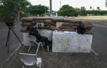 Un gendarme français retranché derrière des sacs de sable dans le cadre d'une mission de sécurisation sur un axe menant à l'aéroport de Nouméa, le 7 juin 2024