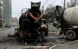 Un homme passe devant des bétonnières incendiées dans une rue d'Irpin, près de Kiev, le 1er avril 2022