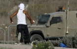 Un Palestinien s'apprête à lancer des pierres en direction d'un véhicule militaire israélien en Cisjordanie près de la ville de al-Ram, nord de Jérusalem le 9 octobre  2016