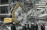 Un engin de chantier déblaie les décombres d'un immeuble en construction détruit par un puissant séisme, le 29 mars 2025 à Bangkok