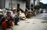 Des hommes sont assis dans une rue bordée d'objets détruits par les pluies et les inondations, entassés dans l'attente des éboueurs, à Hitoyoshi au Japon le 8 juillet 2020