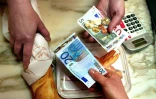 Une personne achète sa baguette de pain, le 2 janvier 2002, dans une boulangerie de Lille, avec un billet de 20 euros