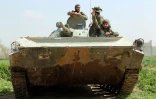Des membres des forces progouvernementales syriennes dans un tank, le 10 mars 2018 à Aftris, dans la Ghouta orientale