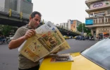 Un Iranien lit un journal dans une rue de Téhéran, le 12 avril 2025, avec en première page les pourparlers irano-américains sur le nucléaire
