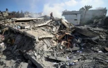 Un membre de la défense civile palestinienne au milieu des décombres d'un bâtiment de la ville de Gaza qui abritait la banque Intaj liée au mouvement Hamas qui contrôle la bande de Gaza, le 15 mai 2021