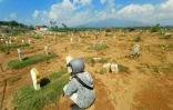Un homme sur la tombe d'un proche dans un cimetière pour les victimes du Covid-19 à Semarang, en Indonésie, le 30 juin 2021