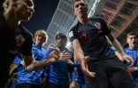 L'avant croate Mario Mandzukic tend la main au photographe de l'AFP Yuri Cortez pour l'aider à se relever, après être tombé sur lui avec ses coéquipiers, en demi-finale de la coupe du monde, le 11 juillet 2018